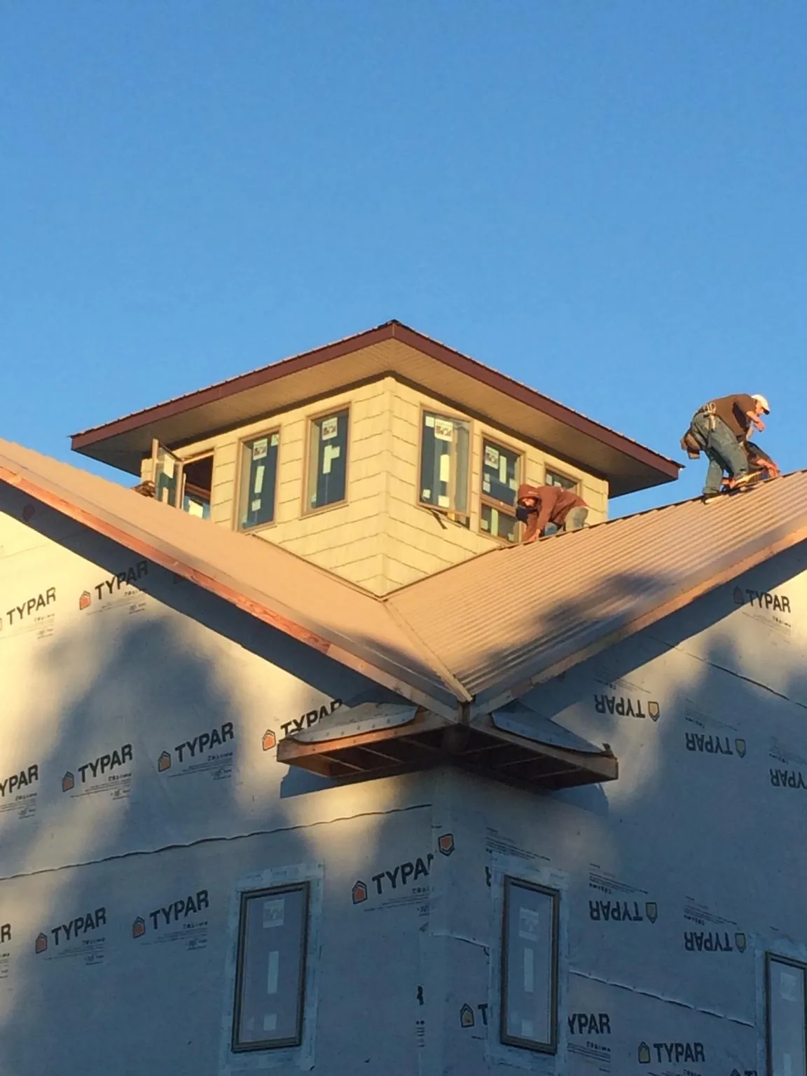 Roofers working around a rooftop cupola on a new metal roof at sunset — Roof Waterproofing in Phoenix by Roofing Brothers